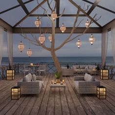 an outdoor seating area with lights hanging from the ceiling and a tree in the middle