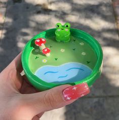 a hand holding a green toy with a frog on it