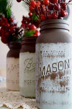 three mason jars decorated with red berries and greenery