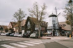 a windmill sits in the middle of a street with parked cars and buildings around it