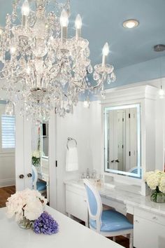 a chandelier hanging from the ceiling in a bathroom with blue walls and white furniture