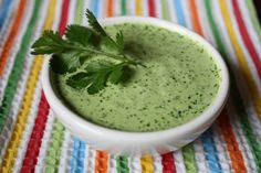 a white bowl filled with broccoli soup on top of a colorful table cloth