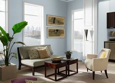 a living room filled with lots of furniture and large windows next to a body of water