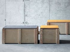 three wooden benches sitting next to each other in front of a concrete wall and cement floor