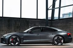 a silver sports car parked in front of a large building with windows on both sides