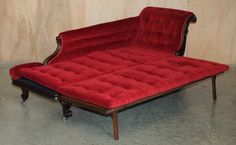 a red couch sitting on top of a hard wood floor next to a wooden wall