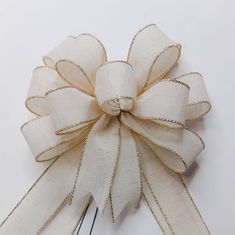 a white bow with gold sequins on the top and bottom is attached to a pair of scissors