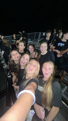 a group of young women standing next to each other on top of a boat at night