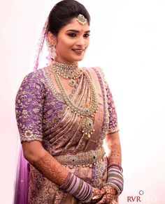 a woman in a purple and gold bridal outfit with her hands on her hips