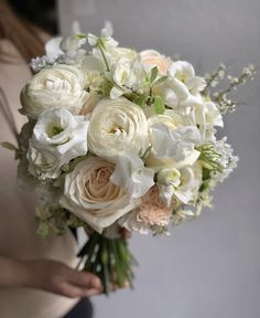 a woman holding a bouquet of white and pink flowers