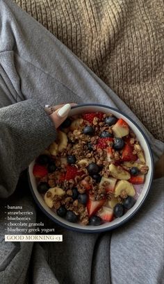 a person holding a bowl of cereal and fruit on their lap, with the caption