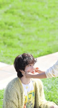 a woman sitting on the ground next to a man in a white shirt and yellow sweater