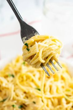 a fork full of pasta with cheese and parsley on the top, in a white bowl