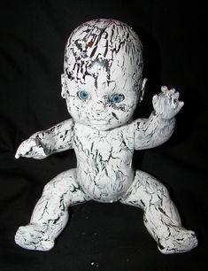 a white baby doll with blue eyes on a black background