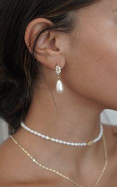 a close up of a woman wearing a necklace and earring with pearls on it