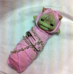 a small doll in a pink dress with chains around it's neck and eyes