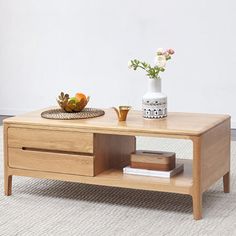 a coffee table with two drawers and a vase on top, in front of a white wall