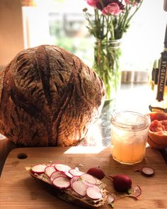 a loaf of bread sitting on top of a cutting board next to sliced radishes