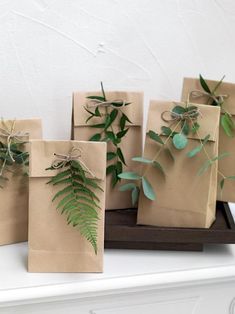 four brown bags with green leaves tied to them on a shelf in front of a white wall