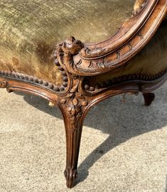 an ornate wooden chair with velvet upholstering on the armrests and back