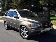 a silver suv parked on the street in front of a house with trees behind it