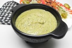 a black bowl filled with guacamole on top of a white tablecloth