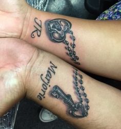 two people with tattoos on their arms holding each other's hands and one has a key