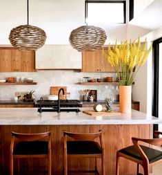 a kitchen with wooden cabinets and counter tops, two hanging lights above the stove top