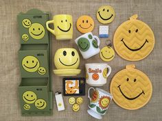 a table topped with lots of different types of smiley face coasters and mugs