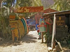 there are many surfboards lined up on the side of the road in front of this shack