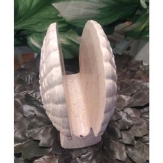 a white vase sitting on top of a table next to a green leafy plant