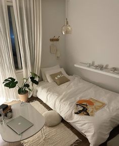 a small bedroom with a bed, desk and laptop on the floor in front of a window