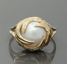 A Lovely Vintage Ladies Mabe Pearl Ring crafted in 10K Yellow Gold.  The Nice sized Pearl Is held in place by circular wisps of Gold.  A Very Pretty Design.  The Mabe Pearl is very clean with a hint of rainbow colors visible as you move the ring.  Easy to picture on a ladies hand as it has such a timeless design.   Stone:  Mabe Pearl (approx.  15mm) Metal:  10K Yellow Gold Ring Size:  10 Total Weight:  4.7 Grams Hallmarks:  10K Condition:  In excellent condition with no stone chips and very minor scuffing to the metal as viewed under 10X magnification. Item# 1097 Mabe Pearl Rings, Luxury Vintage Gold Pearl Ring, Luxury Antique Gold Pearl Ring, Antique Yellow Gold 14k Pearl Ring, Vintage Gold Hallmarked Pearl Ring, Antique Jewelry Rings, Stone Chips, Mabe Pearl, Ring Crafts