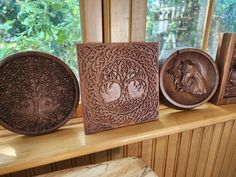 four carved wooden plaques sitting on top of a shelf next to a window sill