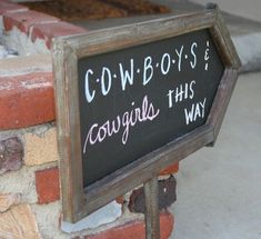 a sign that says cowboys is cowgirls this way on the side of a brick wall