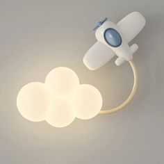 a light that is on top of a cloud shaped wall mounted lamp with a plug in the middle