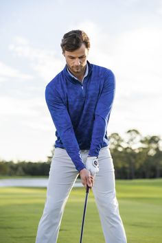 a man in blue shirt and white pants playing golf