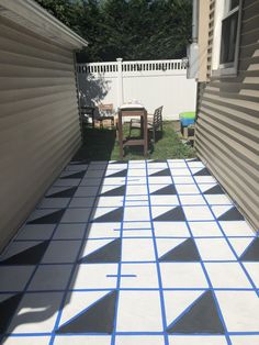 an outdoor patio with blue and white tiles on the ground, next to a house