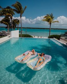 two women lounging on inflatable rafts at the edge of a swimming pool