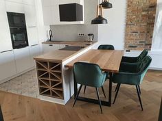 a kitchen with an island table surrounded by green chairs