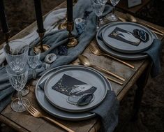 the table is set with silver and black place settings, napkins, glasses, and candles