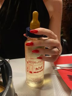 a woman with red nails is holding a baby bottle