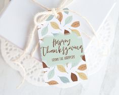 a tag that says happy thanksgiving with leaves on it next to a lace doily