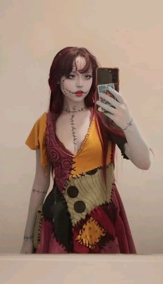 a woman with makeup and body art taking a selfie in front of a mirror