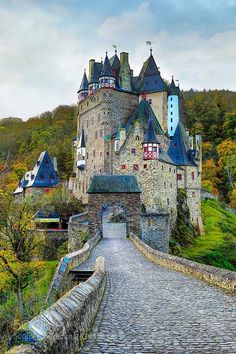 an old castle is shown on the side of a hill with cobblestone roads