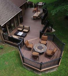 an aerial view of a deck with chairs and fire pit in the center, surrounded by green grass