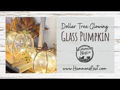 two glass pumpkins sitting on top of a table next to a sign that says dollar tree glowing glass pumpkin