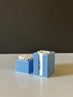 a small blue box with toothbrushes in it on a table next to a wall