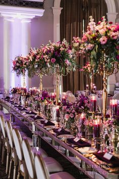 a long table is set with candles and flowers in tall vases on each side