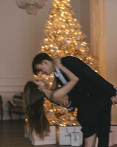 a man and woman dancing in front of a christmas tree